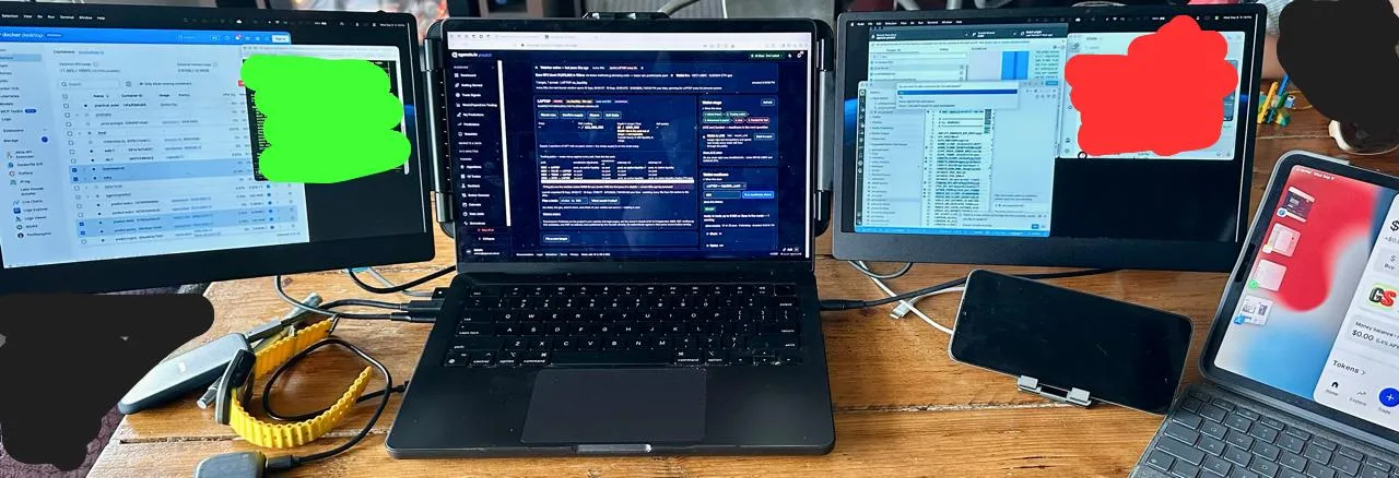Three screens set up on a dining-room table: Docker Desktop and a container list on the left, the launch radar's tracker in the middle with the LAPTOP target open, a code editor on the right, and a phone and tablet propped up beside them. Two panels are painted over in green and red.